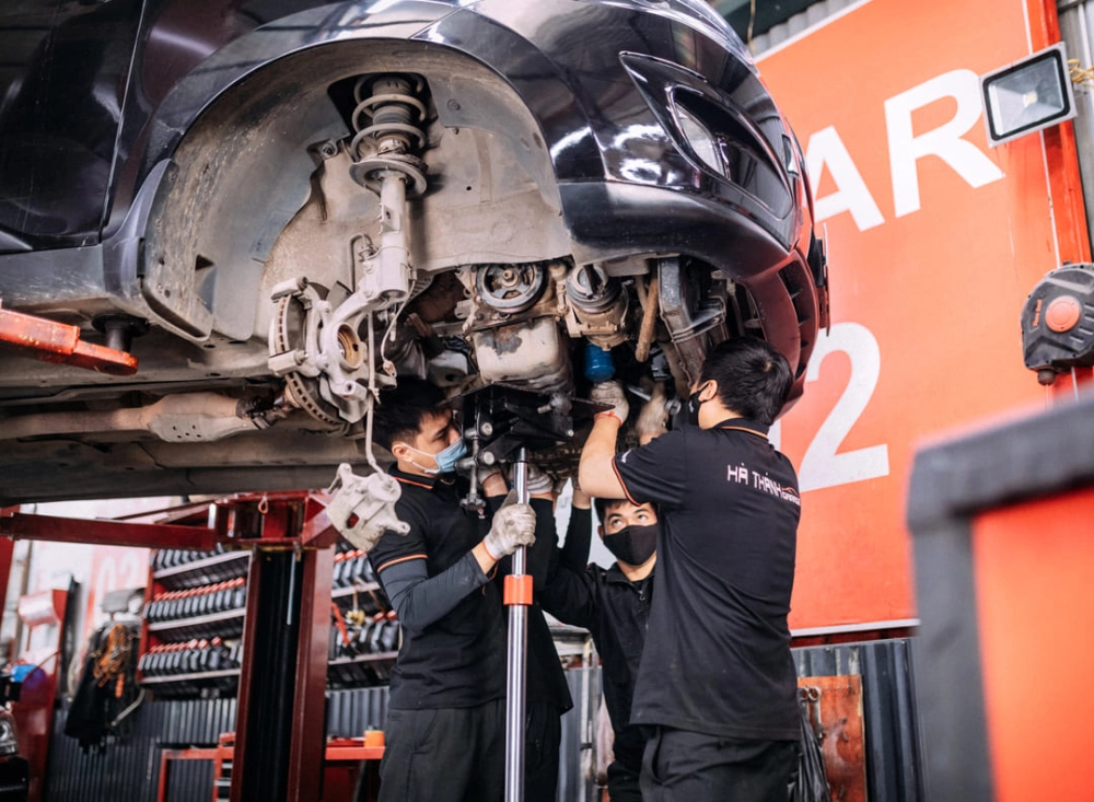 Một chiếc xe đang được kiểm tra tại gara với kỹ thuật viên sử dụng thiết bị hiện đại